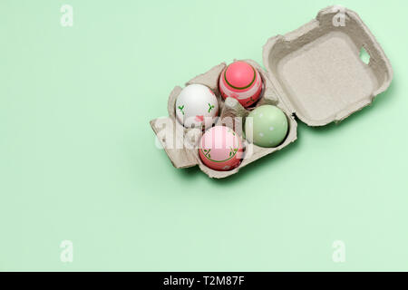 paper container with decorated easter eggs on a green background Stock Photo