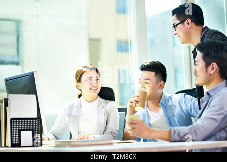 four young asian businesspeople meeting in office discussing business plan using tablet PC. Stock Photo