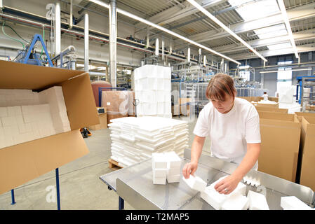 woman works in the shipping department of a company and packs styrofoam components into packages for the customer. Stock Photo