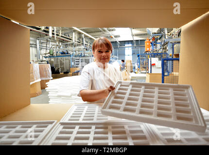 woman works in the shipping department of a company and packs styrofoam components into packages for the customer. Stock Photo