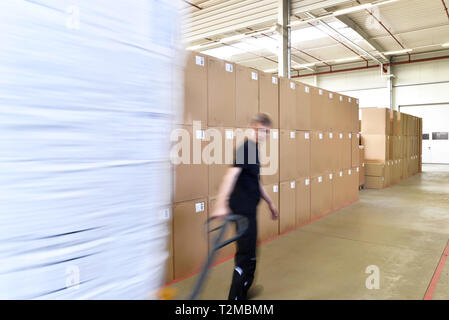 young worker in industrial plant working with forklift in warehouse Stock Photo