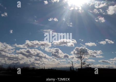 bright sky with altocumulus clouds and sun shining with rays of light Stock Photo