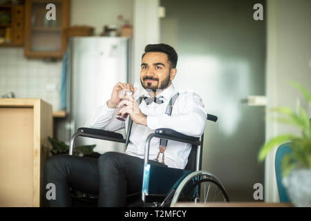 Businessman having drink in wheelchair Stock Photo