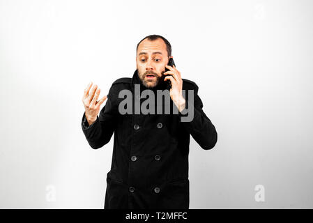 Middle-aged man with overcoat screams angrily at his mobile phone, isolated on white. Stock Photo