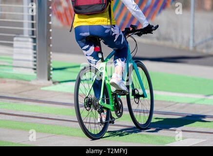 A woman cyclist in sportswear crosses the tram rails on a bicycle, preferring an active way of relaxation, helping her to keep herself in good shape,  Stock Photo