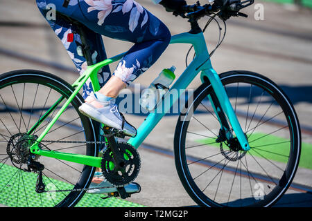 A woman cyclist in sportswear crosses the tram rails on a bicycle, preferring an active way of relaxation, helping her to keep herself in good shape,  Stock Photo