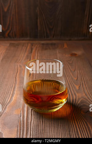 Snifter glass with pure whiskey on wooden table Stock Photo