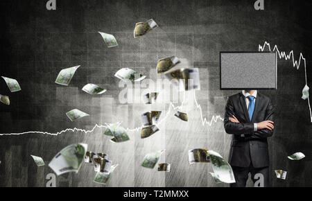 Businessman in suit with TV instead of head keeping arms crossed while standing against flying euros and analytical charts drawn on wall on background Stock Photo