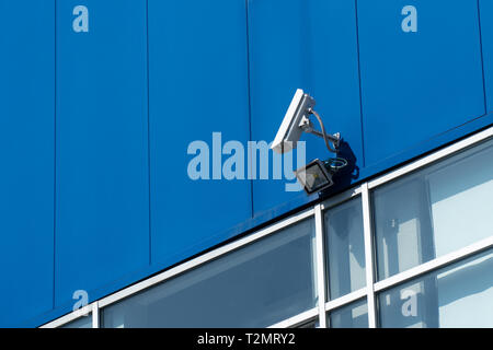 Surveillance concept. Security camera on blue building facade Stock Photo