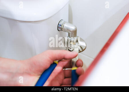 Sanitary worker performs repair of toilet bowl, broken pipe Stock Photo