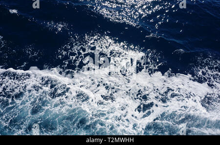 Dark blue deep sea surface, rippled water with sea foam and sparkling light Stock Photo