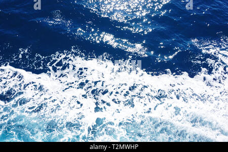 Light blue rippled sea surface with white sea foam, small waves and sparkles Stock Photo