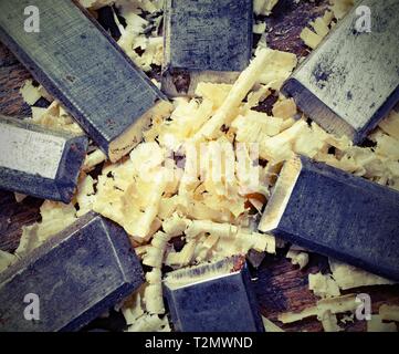 sharp steel blades many chisels and sawdust chippings on the workbench with old toned effect Stock Photo