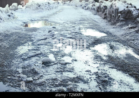Melting snow and puddles on the road. Spring afternoon. Stock Photo
