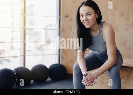young girl in sportswear in a gym in a simple background, a theme of fitness and sport, a healthy lifestyle Stock Photo