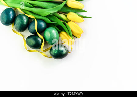 Beautiful spring concept with Easter eggs and yellow tulips on isolated white background. Copy space. Stock Photo