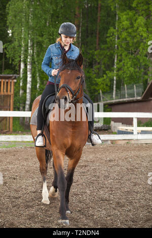 Beginner riding lessons, teenage girl rides a horse on riding field, vertical photo Stock Photo
