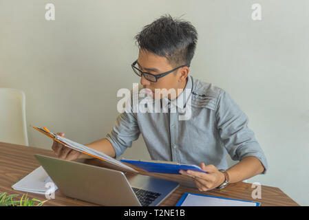 Young Asian manager reading reports in the office Stock Photo
