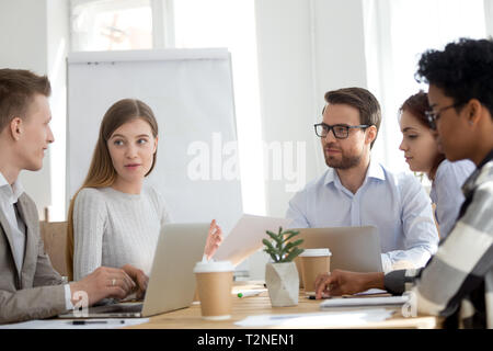 Five diverse multiracial business people colleagues working using computers sitting together at the desk in office boardroom at meeting briefing. Boss Stock Photo