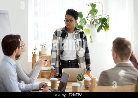 Businesspeople at seminar sitting in office working using computer in boardroom. African black serious leader boss female stands communicate listen wi Stock Photo