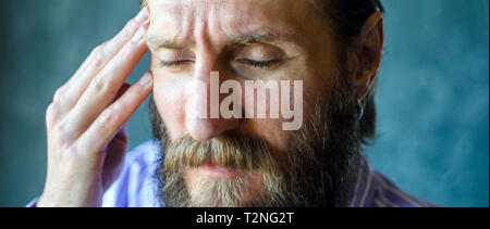 Close-up Portrait of a Man's Face Closed Eyes Suffering a Headache Symptom of the Disease. Bearded Man Massaging His Right Temple with His Fingers. Wr Stock Photo