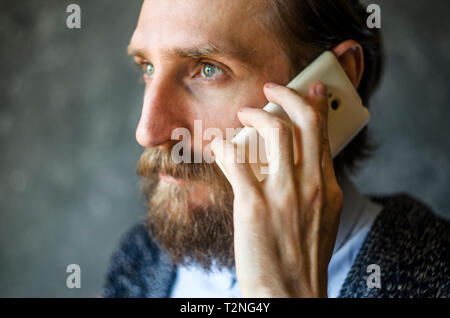 Bearded Man Talking on a Mobile Phone with Indifference. Difficult Telephone Conversation Concept Stock Photo