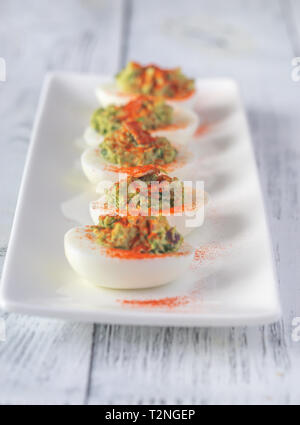 Guacamole and bacon deviled eggs on the white plate Stock Photo