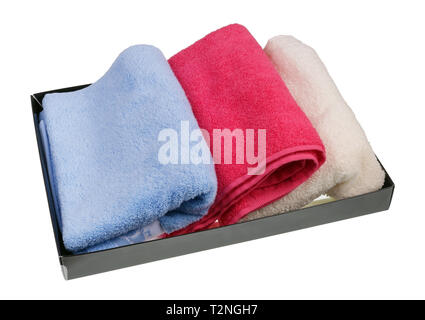 Colored terry new bath towels in a cardboard box. Isolated on white studio closeup Stock Photo