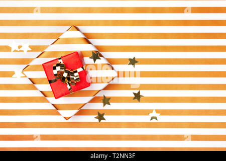 Top view of two gift boxes wrapped in red and striped paper with golden bow on striped bronze paper. Christmas and holiday card. Stock Photo