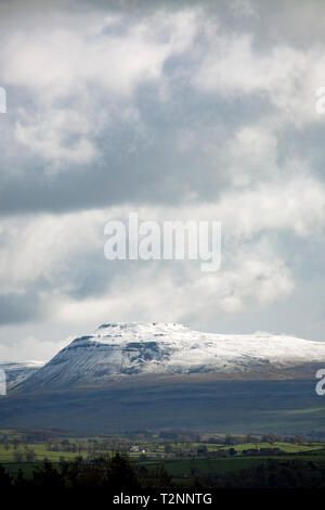 Ingleborough mountain with a covering of snow under clouds on April 2 2019. Ingleborough is popular with hill walkers and forms part of the Three Peak Stock Photo