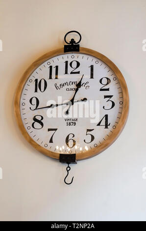vintage wall clock on a white wall with side window light Stock Photo