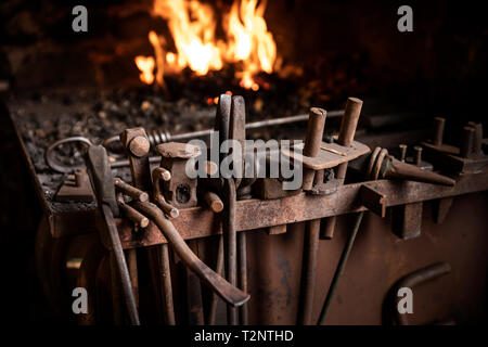 Row of tools in front of fire in blacksmiths workshop Stock Photo