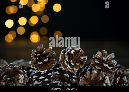 selection of pine cones on a wooden table with bokeh lights in the back. Can be used as a background Stock Photo