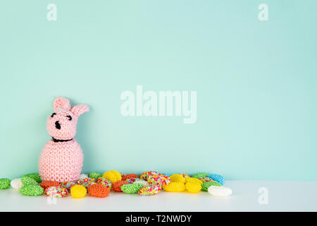 stuffed bunny toy with colored candy in front of an colored background, with space next to it Stock Photo