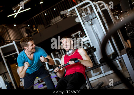 Young man with trainer doing exercise in the modern gym Stock Photo