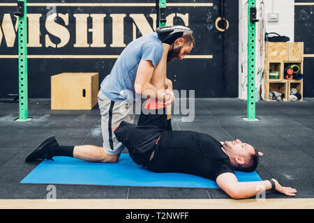 Personal trainer working with man with disability in gym Stock Photo
