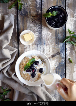 Summer breakfast with porridge, cream and blackberries at village summer home Stock Photo