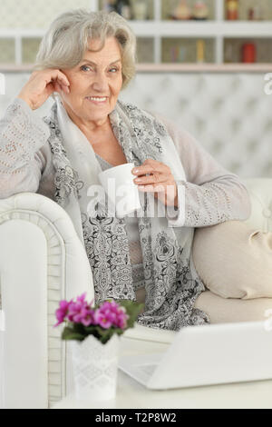 Portrait of senior woman using laptop while sitting on sofa Stock Photo
