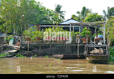 Can Tho, Vietnam - December 31st 2017. Two men work in the garden at back of their house which looks out onto a waterway in the Mekong Delta Stock Photo