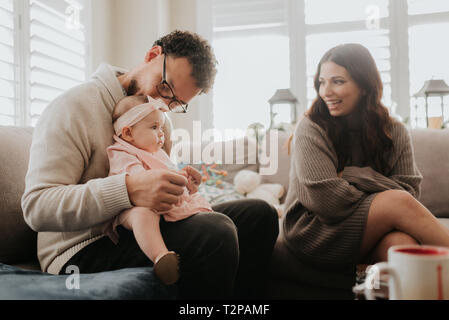 Couple playing with baby daughter on sofa Stock Photo