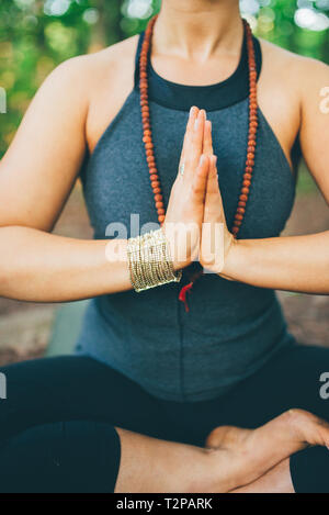 Woman doing prayer pose in forest Stock Photo