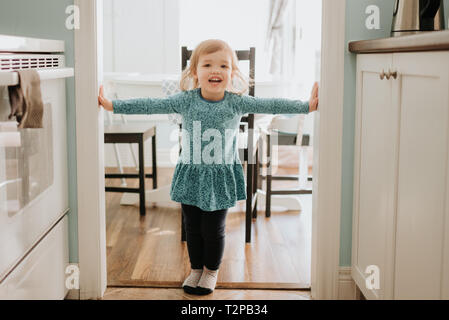 Female toddler standing in kitchen doorway, portrait Stock Photo