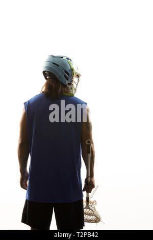 Young male lacrosse player holding lacrosse stick, rear view against white background Stock Photo