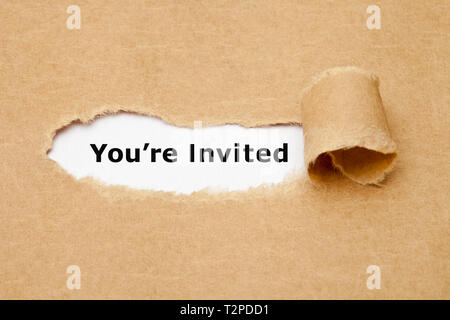 Text You Are Invited appearing behind torn brown paper. Invitation concept. Stock Photo