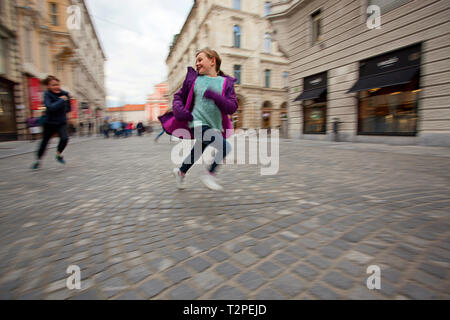 Young boy chasing girl in the street, Ljubljana, Slovenia Stock Photo