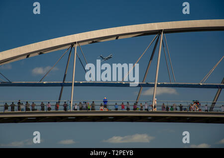 A C-5 military plane from Amberley airbase performs a fly-over of Brisbane River as crowds on Goodwill Bridge look on Stock Photo