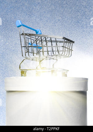 Shopping trolley on a round white gift box on a winter blue shiny background with bright rays. The best buyer or the best purchase. Stock Photo