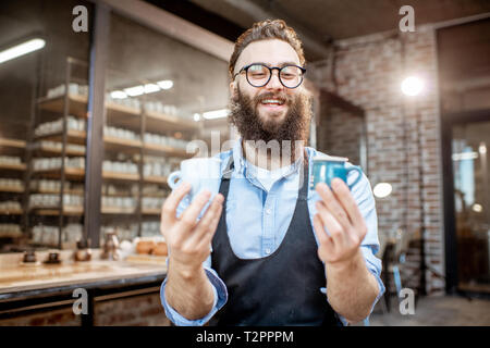 Portrait of a creative bearded potter man holding ceramic products at the pottery shop Stock Photo
