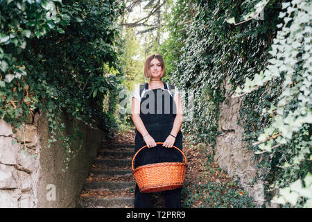 Woman with basket descending ivy-covered stairs Stock Photo