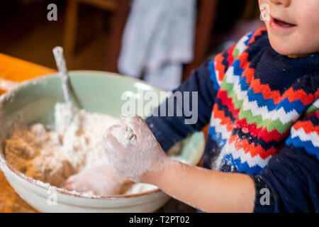 Toddler playing with flour in mixing bowl Stock Photo